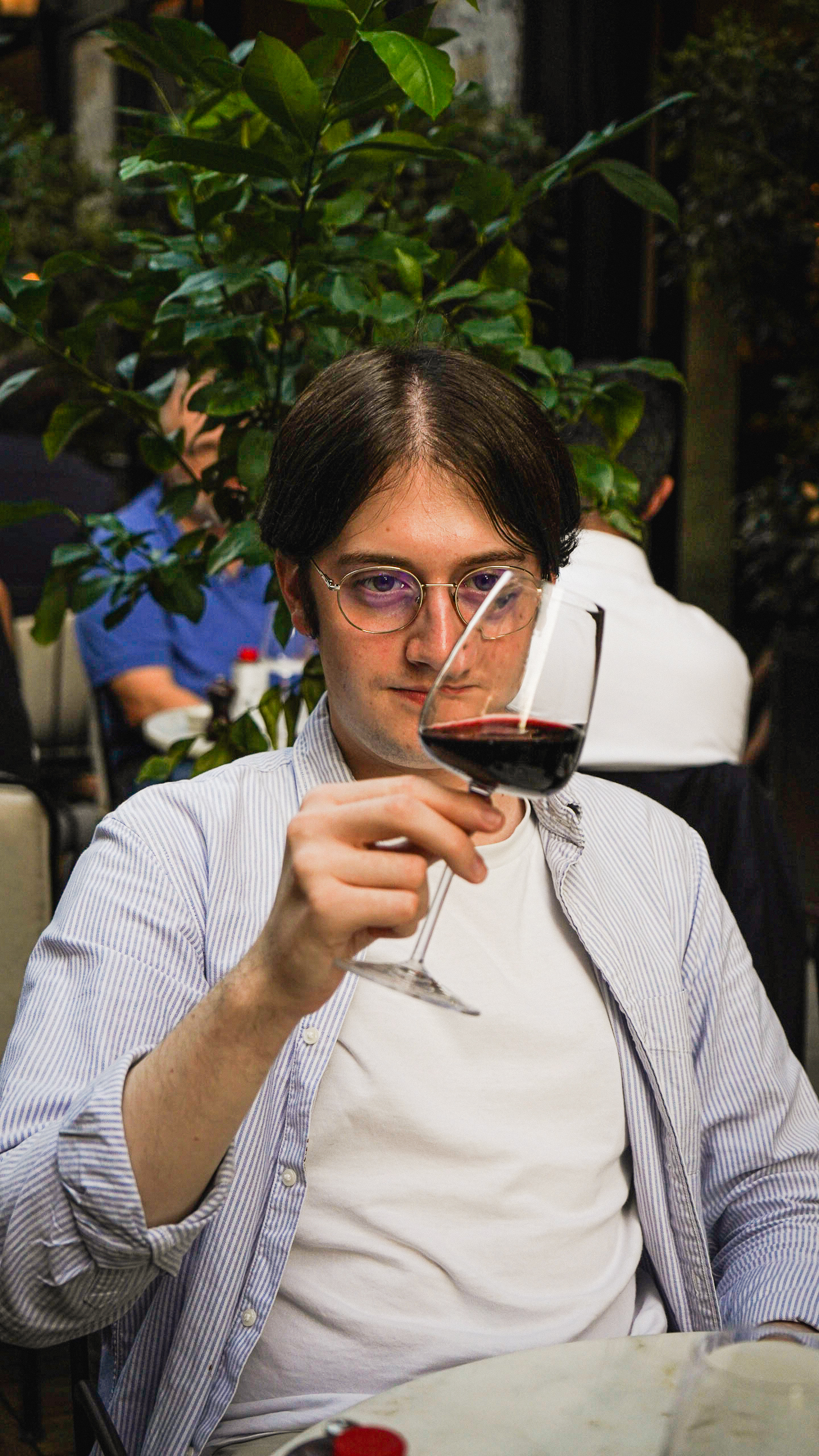 A French guy in Paris eating in a restaurant while holding a glass of red wine